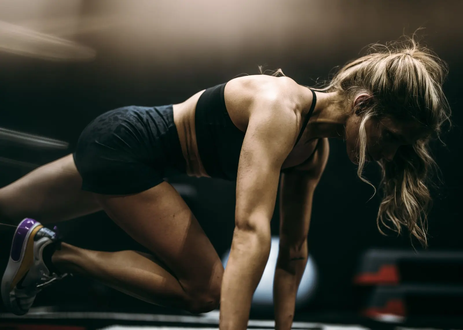 Woman doing mountain climbers on a dark gym floor
