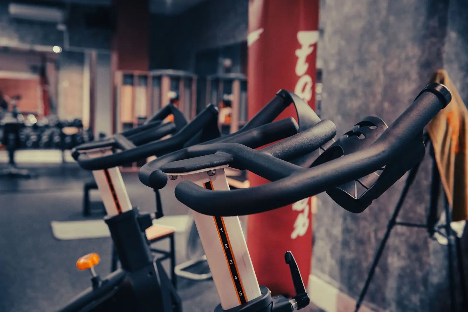 Row of indoor cycling bikes in a dimly lit studio